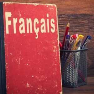 bureau sur lequel sont posés un manuel de français et un pot de stylos