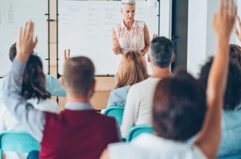 formatrice de français devant un tableau blanc dans une classe d’adultes